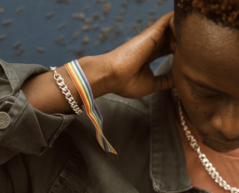 A man wearing a rainbow bracelet