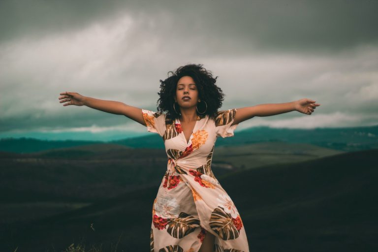A black woman with glorious hair, arms spread in freedom